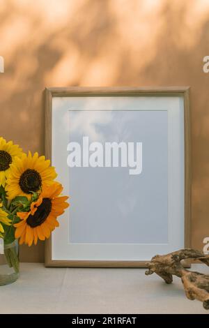 Vase gefüllt mit Sonnenblumen neben einem leeren Bilderrahmen Stockfoto