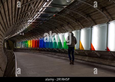 Ein Mann, der durch einen Tunnel mit bunten Wänden geht Stockfoto