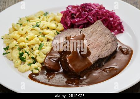 Sauerbraten (zartiertes Rindfleisch, das mehrere Tage in Essig und Gemüse mariniert und dann geschmort wurde), Rotkohl (geschmorter Rotkohl), Spaetzle (kleine Vergangenheit Stockfoto