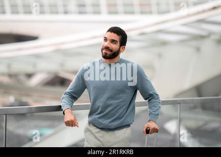 Ein Fröhlicher Tourist Aus Dem Nahen Osten, Der Am Flughafen Zur Seite Blickt Stockfoto