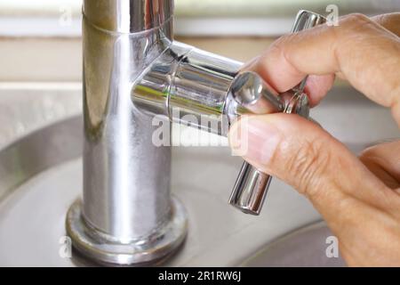 Person, die einen Wasserhahn zum Händewaschen aufdreht Stockfoto