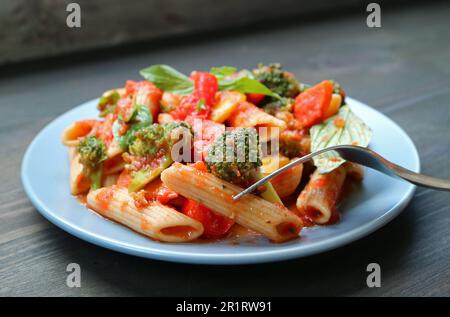 Würzige Penne mit Gabel pflücken und gebratenem Gemüse in Tomaten-Basilikum-Sauce Stockfoto