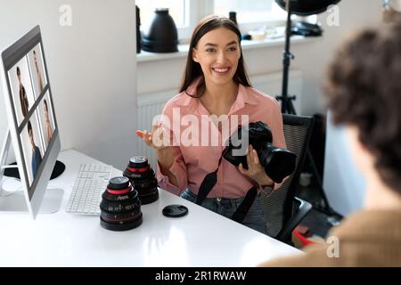 Die Kunst des Feedbacks. Junge Fotografin, die dem Kerl die Ergebnisse der Fotografie zeigt, und Fotos auf dem Computermonitor diskutiert Stockfoto