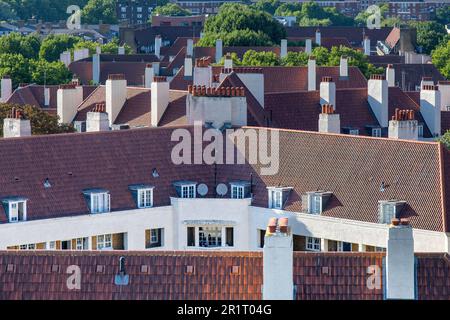 London, England-August 2022: Blick auf die einzigartige Architektur der orangefarbenen Dächer, Fenster und weißen Schornsteine des Levita House Stockfoto