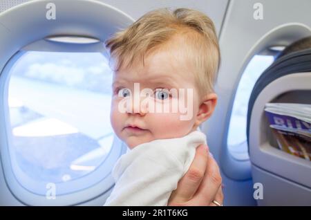 Mutter, die mit einem sechs Monate alten Mädchen in einem Flugzeug reist Stockfoto