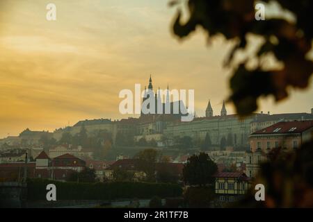 Landschaft mit St. Der Veitsdom bei Sonnenuntergang wurde im Herbst in Prag, Tschechische Republik, durch das Laub geschleudert. Stockfoto