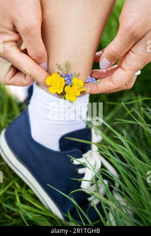 Wunderschöne Freizeitschuhe mit zarten, leuchtenden Farben in Socken. Modische, stylische sportliche Freizeitschuhe. Blumen in blauen Turnschuhen, ein Klassiker. Nahaufnahme Stockfoto