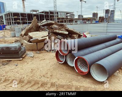 Baustelle. Polypropylenrohre liegen auf feinem Sand. Nahe gelegene Betonblöcke für den Bau von Häusern, Straßen. Bau von Häusern im c Stockfoto