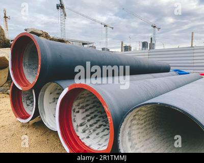 Baustelle. Polypropylenrohre liegen auf der Baustelle. Nahe gelegene Betonblöcke für den Bau von Häusern, Straßen. Verlegen von Rohrleitungen, lin Stockfoto