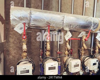 Messgeräte in einem Wohngebäude zur Messung der Wärmeenergie. Messgeräte mit roten Hähnen zum Absperren des Wasserflusses. Stockfoto