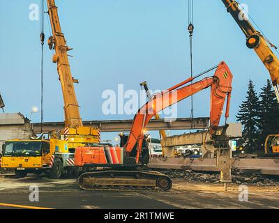 Bau einer gebrochenen Brücke an einer verkehrsreichen Straße. Der Häcksler macht ein Loch in den Asphalt, um ihn zu ersetzen. Die Baustelle ist in der Nähe der Passage Stockfoto