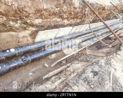 Verlegung unterirdischer Kommunikation für Wohngebäude. Schwarze Rohrleitungen aus langlebigem und zuverlässigem Material liegen auf dem Fundament für d Stockfoto