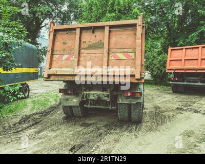 Ein riesiger Lkw mit Aufbau für den Transport schwerer Dinge. Aufkleber für schwere Nutzfahrzeuge auf der Rückseite der Karosserie. Das Auto fährt auf einer schmutzigen, nassen Straße. Stockfoto