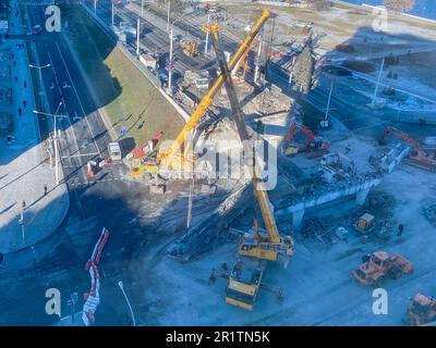 Bau einer neuen Überführung im Stadtzentrum. In der Nähe des Flusses, Wanderweg und viele Gebäude. Die Brücke ist gebrochen, direkt an einer belebten Straße mit C. Stockfoto