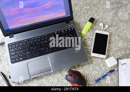 Arbeitsplatz zu Hause, Heimbüro für Fernarbeit mit Computer, Laptop, Mobiltelefon, Smartphone, Notizblock, Stift, Kopfhörer und Brille. Stockfoto