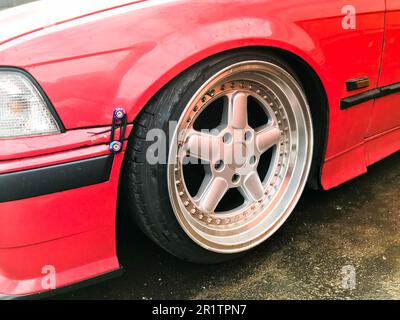 Wunderschöne große Rennräder eines roten Sportwagens mit sehr geringer Bodenfreiheit auf glänzenden, teuren Leichtmetallfelgen im Stil von Stans. Einstellung ca. Stockfoto