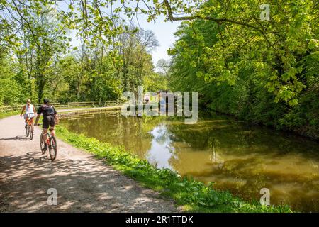 Menschen, die mit dem Fahrrad auf dem Kanal des Peak Forest Canal in Marple in Cheshire England fahren Stockfoto