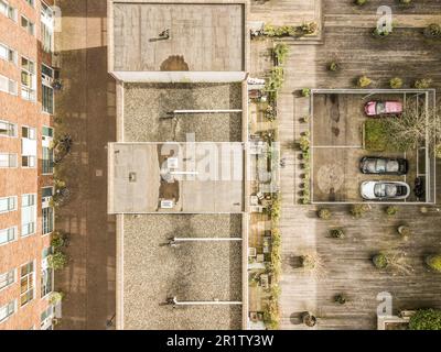 Ein Parkplatz mit seitlich geparkten Autos und Gebäuden im Hintergrund, aus der Vogelperspektive Stockfoto