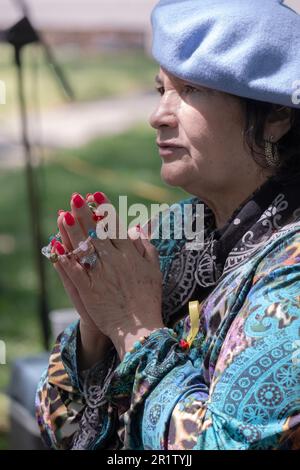 Eine göttliche römisch-katholische Frau betet und meditiert, während sie handgehaltene Rosenkranzperlen hält. Bei einer Krönungszeremonie im Mai in einem Park in Queens, New York City. Stockfoto