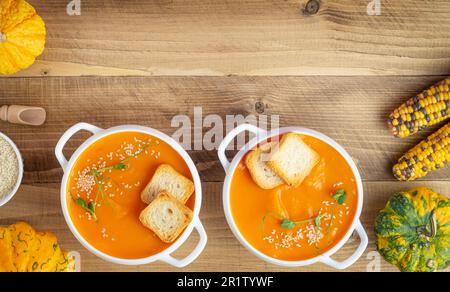 Kürbissuppe mit Croutons und Sesamsamen auf Holzhintergrund. Stockfoto