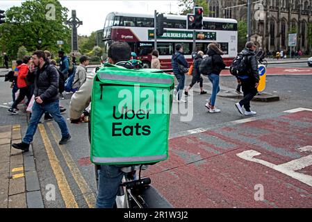 Uber isst einen Lieferradfahrer, der an der Ampel auf der Princes Street, Edinburgh, Schottland, Großbritannien, wartet. Stockfoto