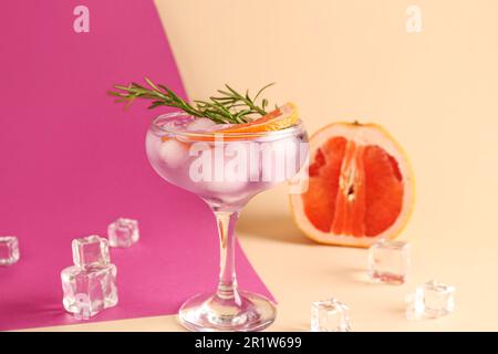 Purpurfarbener Gin und Tonic mit Eiswürfeln auf farbigem Hintergrund Stockfoto