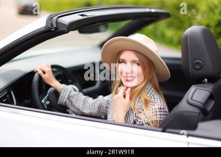 Porträt eines jungen blonden Mädchens mit Hut im Cabriolet Stockfoto