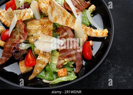 Köstlicher Caesar Salat garniert mit knusprigem Speck, gegrilltem Hähnchen und Parmesan Käse Stockfoto