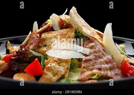 Köstlicher Caesar Salat garniert mit knusprigem Speck, gegrilltem Hähnchen und Parmesan Käse Stockfoto