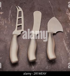 Satz eleganter Käsemesser isoliert auf grauem Schieferhintergrund. Stockfoto