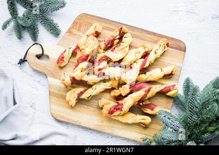 Blätterteigstöcke. Nahaufnahme von herzhaftem Blätterteig mit Prosciutto und Oliven. Idee für ein Rezept mit Vorspeisen. Hochwertiges Foto. Stockfoto