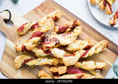 Blätterteigstöcke. Nahaufnahme von herzhaftem Blätterteig mit Prosciutto und Oliven. Idee für ein Rezept mit Vorspeisen. Hochwertiges Foto. Stockfoto