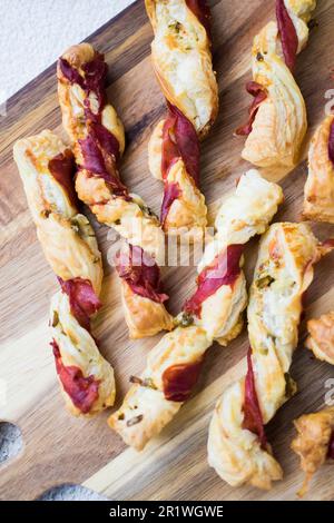 Blätterteigstöcke. Nahaufnahme von herzhaftem Blätterteig mit Prosciutto und Oliven. Idee für ein Rezept mit Vorspeisen. Hochwertiges Foto. Stockfoto