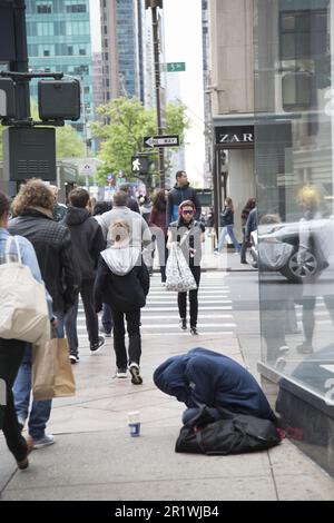 Ein Obdachloser bettelt an der 5. Avenue, sitzt auf dem Bürgersteig in Midtown Manhattan, New York City. Stockfoto