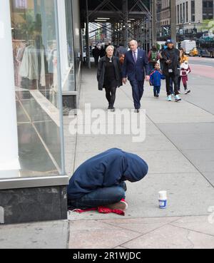 Ein Obdachloser bettelt an der 5. Avenue, sitzt auf dem Bürgersteig in Midtown Manhattan, New York City. Stockfoto