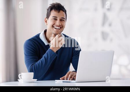 Das Geschäft boomt. Abgeschnittenes Porträt eines gutaussehenden jungen Geschäftsmanns, der aufmerksam aussah, während er im Büro an seinem Laptop arbeitete. Stockfoto