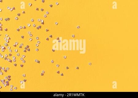 Konfetti aus silbernem Kristall auf gelbem Hintergrund. Leuchtende Komposition mit Kopierraum. Stockfoto