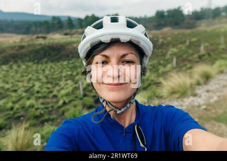 Glücklicher Radfahrer mit Helm, der ein Selfie macht. Hochwertiges Foto Stockfoto