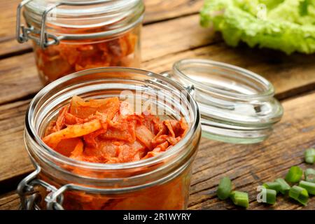 Köstlicher Kimchi mit Chinakohl und Zutaten auf Holztisch, Nahaufnahme Stockfoto