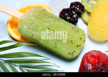 Köstliches Eis am Stiel, frisches Obst und Blätter auf hellem Hintergrund, Nahaufnahme Stockfoto