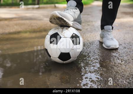 Mann mit Fußball in der Nähe der Pfütze, Nahaufnahme Stockfoto