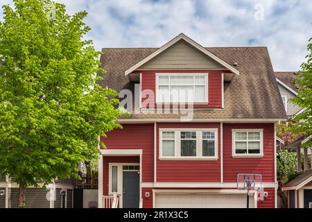 Häuser in einem Vorort in Nordamerika. Dach eines Hauses mit schönen Fenstern über dem blauen Himmel. Wunderschöne Außenansicht Des Hauses. Außenansicht Des Immobiliengebäudes. - Nein Stockfoto