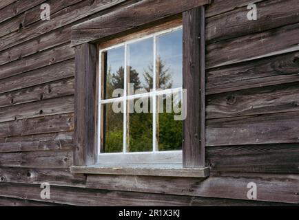 Fenster aus altem Holzhaus auf dem Land. Alte Hütte und Fenster auf dem Land. Rustikales Haus. Niemand, selektiver Fokus, Straßenfoto Stockfoto