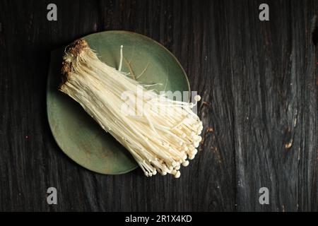Frischer Golden Needle Pilz oder Jamur Enoki, Enokitake (Flammulina velutipes). Beliebt in asiatischer Küche, Blick von oben auf Holzhintergrund Stockfoto