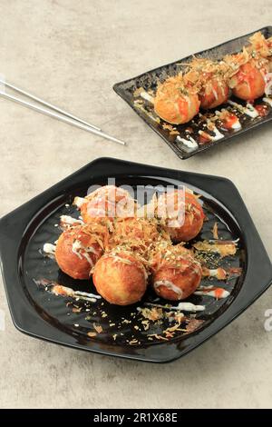 Japanisches Essen, Takoyaki-Bälle mit Tintenfisch auf schwarzem Teller. Essen Auf Dem Sommerfestival Stockfoto