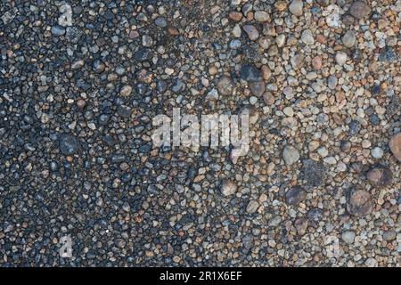 Nahaufnahme von kleinen Felsen, Bodenoberfläche, schwarzgrauem Straßenstein oder Kieselsteinen im Vollformat, Hintergrundstruktur Stockfoto