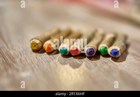 HANDGEFERTIGTER RUSTIKALER BUNTSTIFT ÜBER EINEM HOLZTISCH. AUS NATÜRLICHEM HOLZKOFFER. Selektiver Fokus, verschwommener Hintergrund. Speicherplatz kopieren Stockfoto