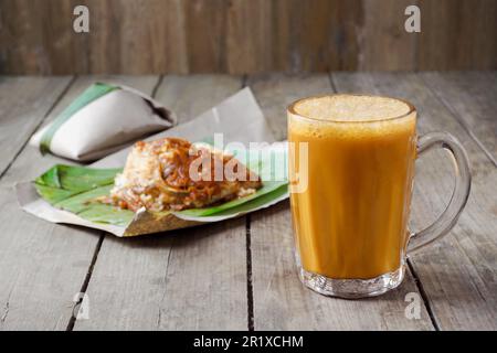 Ein beliebtes Frühstück in Malaysia ist ein heißes Getränk, Tee mit malaiischer Milch, genannt Teh Tarik, zum Essen mit Nasi Lemak Bungkus Stockfoto