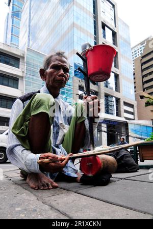 Ein älterer Thailänder, der die Saw Duang spielte, verbeugte das Saiteninstrument auf der Straße im Zentrum von Bangkok, Thailand. Stockfoto