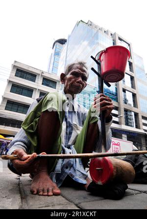 Ein älterer Thailänder, der die Saw Duang spielte, verbeugte das Saiteninstrument auf der Straße im Zentrum von Bangkok, Thailand. Stockfoto